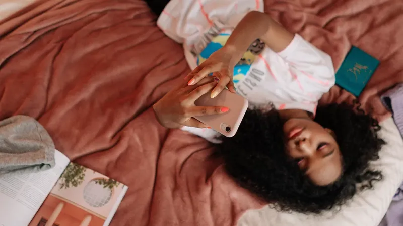 Person laying on bed scrolling phone